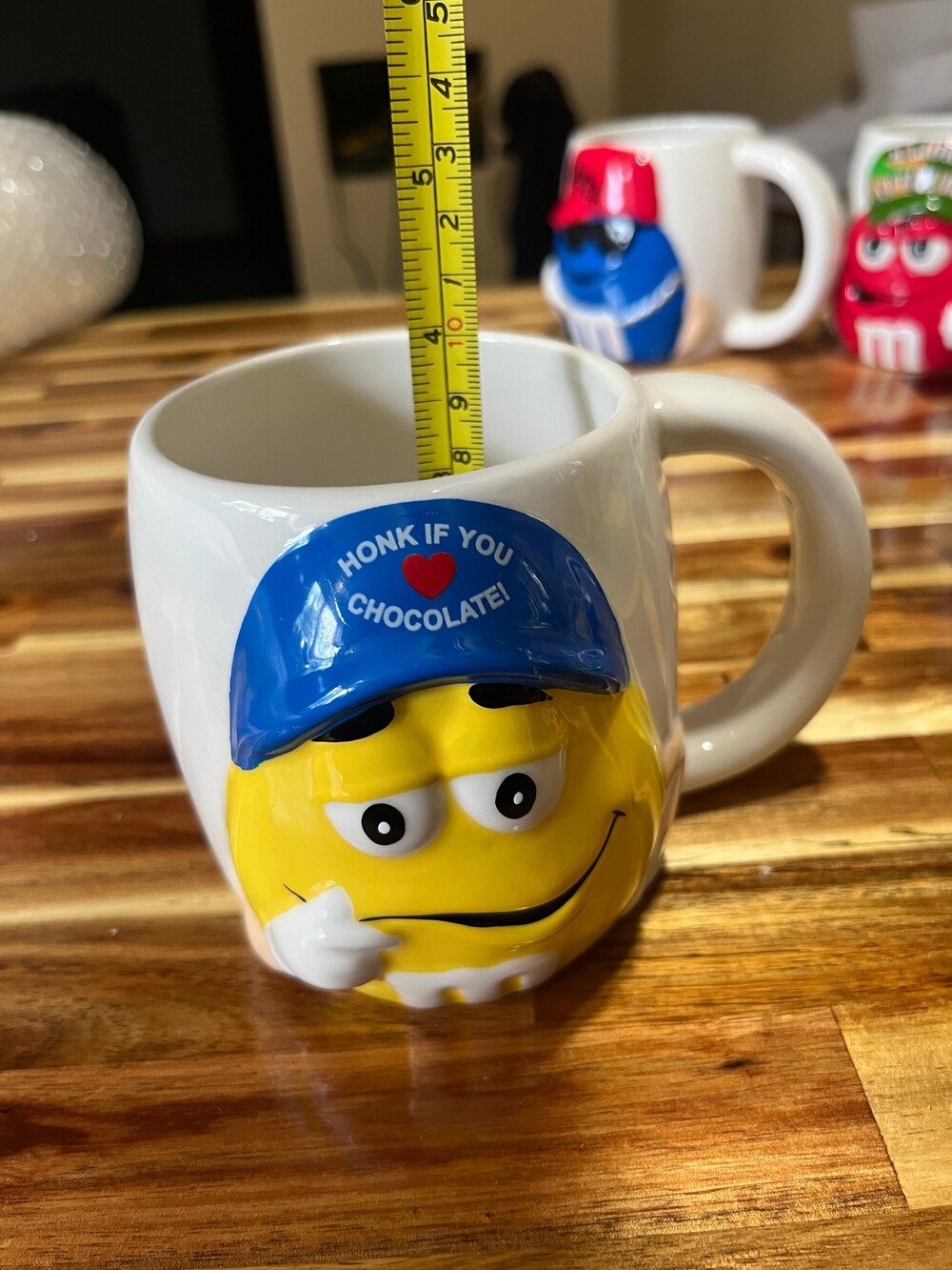 M&M Yellow Character Ceramic Mug featuring a 3D Yellow M&M wearing a blue hat wi